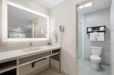 a bathroom with a toilet and a sink and a mirror at Best Western Courtesy Hotel - Anaheim Resort Amusement Park in Anaheim