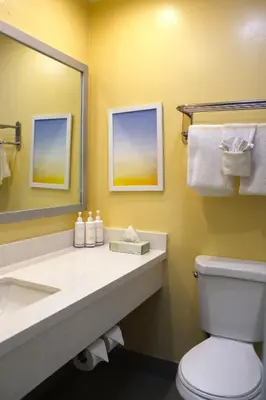 a bathroom with a sink and a toilet and a mirror at Days Inn by Wyndham Los Angeles LAX Airport Stadium Area in Los Angeles