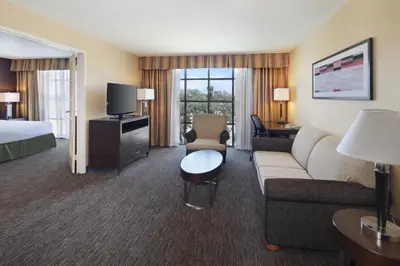 a hotel room with a couch and a bed and a television at Holiday Inn Hotel & Suites Anaheim by IHG in Anaheim