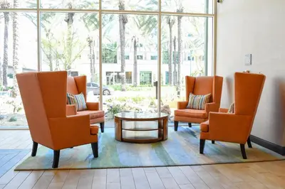 a waiting room with orange chairs and a coffee table at Hotel Indigo Anaheim by IHG in Anaheim