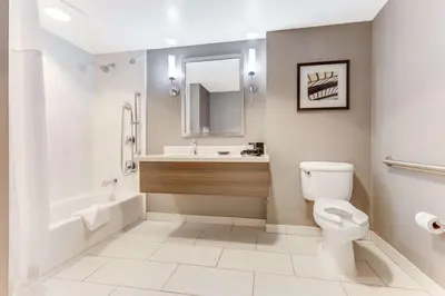 a bathroom with a toilet and a sink and a mirror at Sonesta Anaheim Resort Area in Anaheim