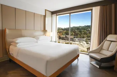 a bedroom with a bed and a chair and a large window at Sheraton Universal in Los Angeles