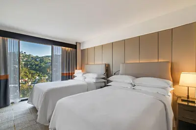 a hotel room with two beds and a large window at Sheraton Universal in Los Angeles