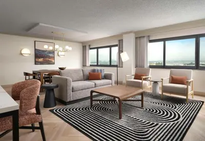 a living room with a couch and chairs and a table at Sonesta Los Angeles Airport LAX in Los Angeles