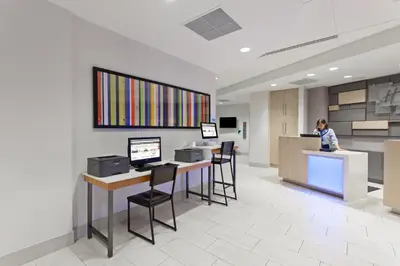a woman standing at a counter in an office lobby at Holiday Inn Express West Los Angeles by IHG in Los Angeles