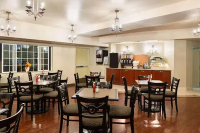 a restaurant with tables and chairs and a kitchen at Hotel Marguerite South Anaheim - Garden Grove, Trademark Collection by Wyndham in Anaheim