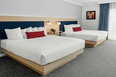 two beds in a hotel room with red pillows at The Live Hotel in Los Angeles