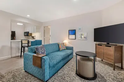 a living room with a blue couch and a flat screen tv at Sonesta ES Suites Torrance Redondo Beach in Torrance