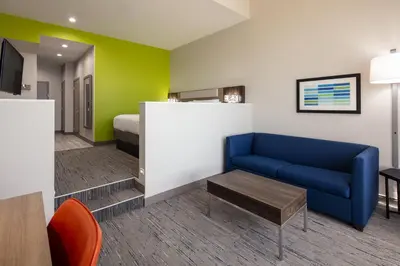 a living room with a blue couch and a bed at Holiday Inn Express Hotel & Suites Ventura Harbor by IHG in Ventura