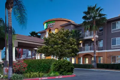 a hotel with a palm tree in front of it at Holiday Inn Express & Suites Corona by IHG in Corona