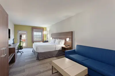 a hotel room with a bed and a blue couch at Holiday Inn Express & Suites Corona by IHG in Corona