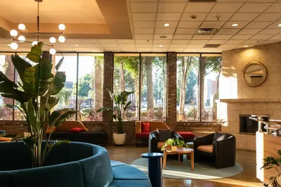 a lobby with couches and plants and windows at Hotel Burbank in Burbank