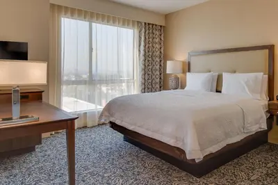 a hotel room with a bed and a large window at Hampton Inn & Suites Los Angeles - Glendale in Glendale