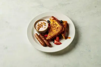 a plate of food with waffles and sausage and sauce at Holiday Inn Diamond Bar - Pomona by IHG in Diamond Bar
