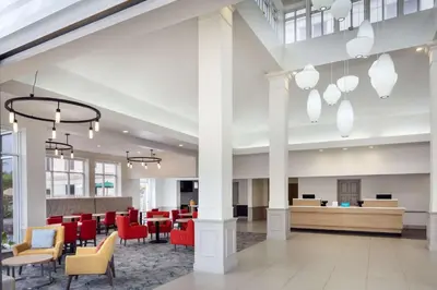 a rendering of a lobby with red chairs and tables at Hilton Garden Inn Arcadia/Pasadena Area in Arcadia