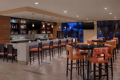 a restaurant with tables and chairs and a bar at Delta Hotels by Marriott Anaheim Garden Grove in Anaheim