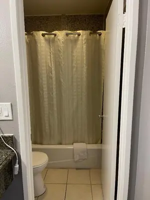 a bathroom with a shower curtain and a toilet at El Segundo Inn in Hawthorne