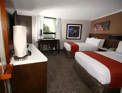 a hotel room with two beds and a desk at Holiday Inn Long Beach - Airport by IHG in Long Beach