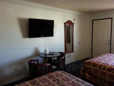 a hotel room with a table and a bed and a tv at Royal Inn Motel Long Beach in Long Beach