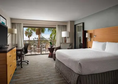 a hotel room with a bed and a balcony at Sonesta Redondo Beach and Marina in Redondo Beach