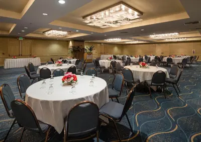 a conference room with tables and chairs with flowers on them at Crowne Plaza Ventura Beach by IHG in Ventura