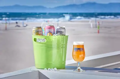 a drink and a glass of beer on a table near the beach at Beach House Hotel at Hermosa Beach in Hermosa Beach