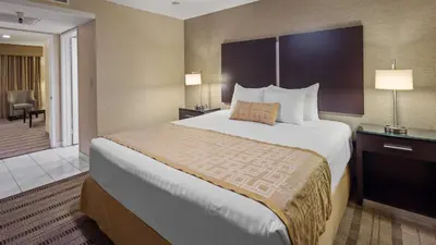 a hotel room with a large bed and a hallway at Best Western Pasadena Royale Inn & Suites in Pasadena
