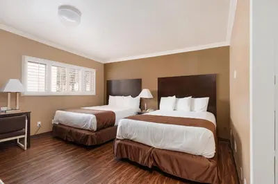 a hotel room with two beds and a desk at Americas Best Value Inn & Suites Anaheim in Anaheim