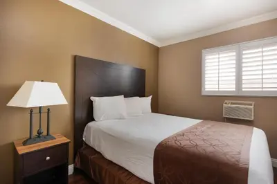 a bedroom with a bed and a lamp and a window at Americas Best Value Inn & Suites Anaheim in Anaheim