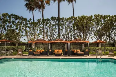 a swimming pool with chairs and umbrellas at DoubleTree by Hilton Carson in Carson