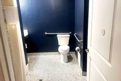 a bathroom with a toilet with a blue wall at Super 8 by Wyndham Hollywood/LA Area in Los Angeles