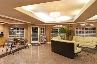 a living room with a couch and a table and chairs at Super 8 by Wyndham Los Angeles Downtown in Los Angeles