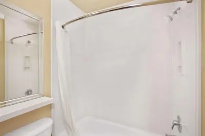 a white bathroom with a shower and a toilet at Super 8 by Wyndham Los Angeles Downtown in Los Angeles