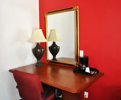 a desk with a mirror and a red wall at A Nights Inn in Ridgecrest
