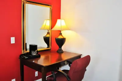 a desk with a mirror and a lamp and a chair at A Nights Inn in Ridgecrest