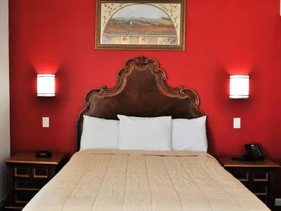 a bedroom with a bed with a red wall at A Nights Inn in Ridgecrest