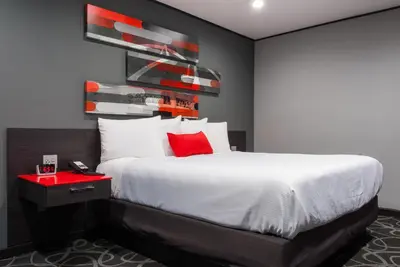 a bedroom with a large bed with red accents at Astro Pasadena Hotel in Pasadena