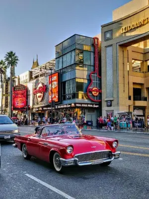 an old red car driving down a city street at Hollywood Panoramic Views, Pool, Gym & Free parking! in Los Angeles