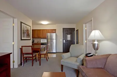 a living room with a couch and chairs and a kitchen at Staybridge Suites Palmdale by IHG in Palmdale