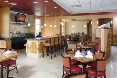 a restaurant with tables and chairs and a bar at Holiday Inn & Suites Bakersfield by IHG in Bakersfield