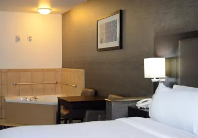 a hotel room with a bed and a bathroom with a tub at Holiday Inn Express & Suites Barstow - Route 66 by IHG in Barstow