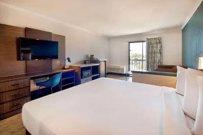 a hotel room with a large white bed and a desk at Studio 6 Suites Lawndale, CA South Bay in Lawndale