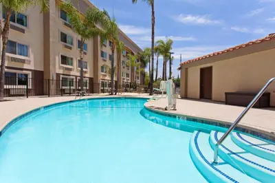 a swimming pool at a hotel with palm trees at Holiday Inn Express San Bernardino Colton by IHG in Colton