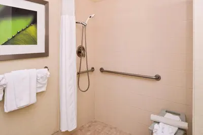 a bathroom with a shower with white towels at Courtyard by Marriott Victorville Hesperia in Hesperia