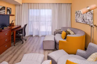 a living room with a couch and a desk and a television at Courtyard by Marriott Victorville Hesperia in Hesperia