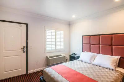 a bedroom with a bed with a red headboard and a window at El Dorado Inn in Lynwood