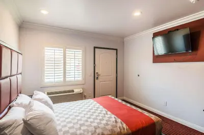 a bedroom with a bed and a tv on the wall at El Dorado Inn in Lynwood