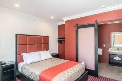 a hotel room with a bed with an orange headboard at El Dorado Inn in Lynwood