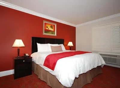 a bedroom with a large bed with a red wall at Best Western Burbank Airport Inn in Los Angeles