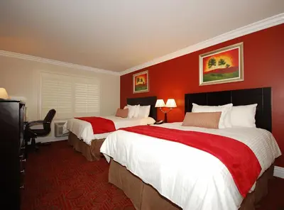 two beds in a hotel room with red walls at Best Western Burbank Airport Inn in Los Angeles